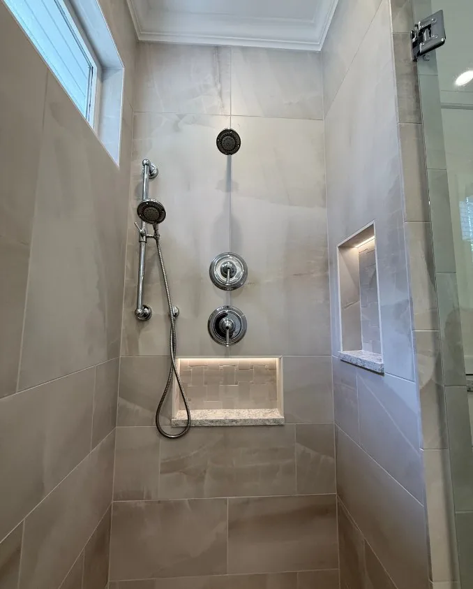 A large tiled shower with a rainfall head and glass enclosure