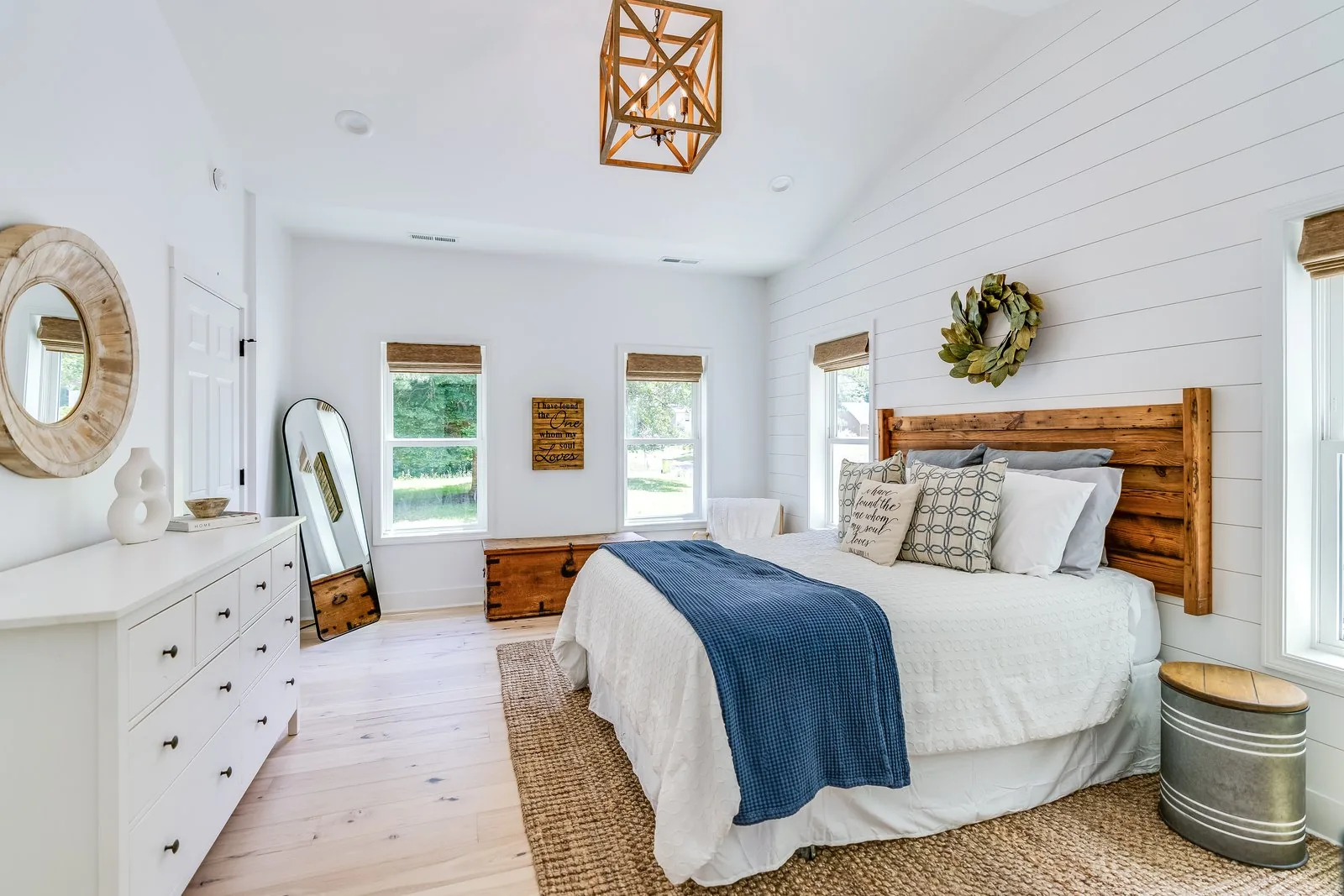 A bedroom with shiplap walls, a reclaimed wood headboard and vaulted ceiling