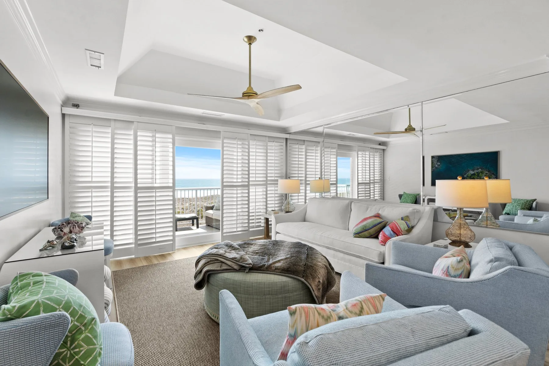 An open coastal living room with plantation shutters and an ocean view, remodeled by Avocet Design Build