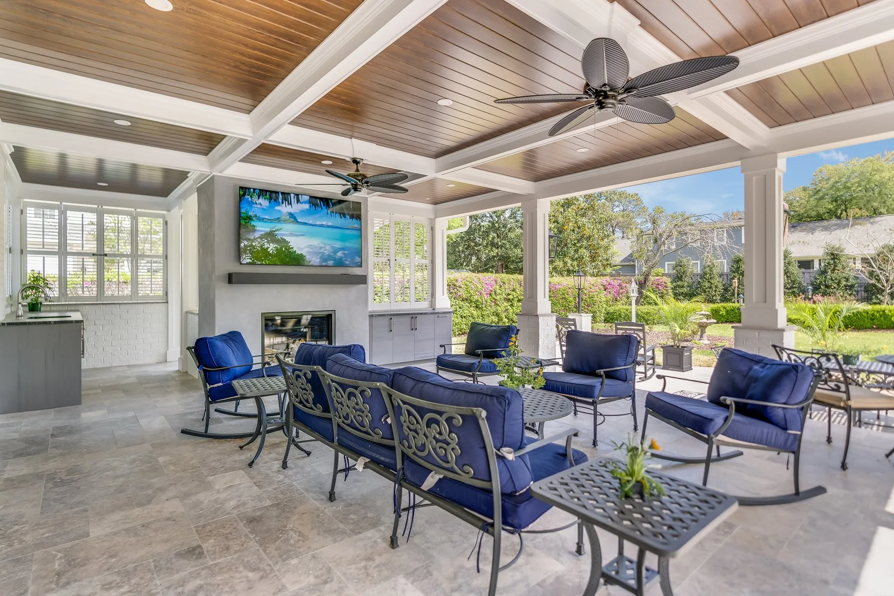 A covered porch addition with a stained wood ceiling, fireplace and outdoor seating