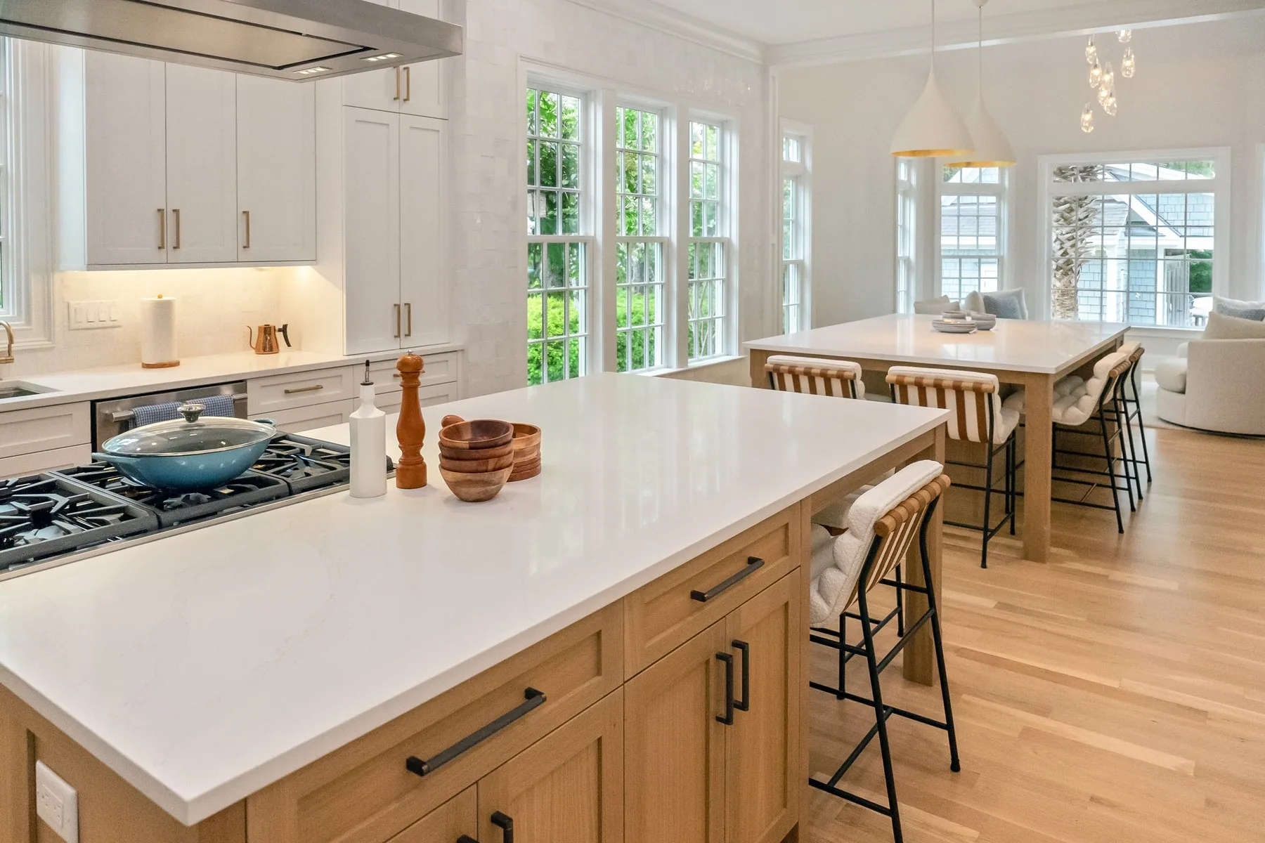 A bright kitchen with two islands, white oak cabinetry and stone countertops